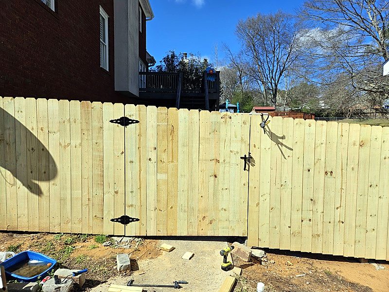Wood privacy fence with a gate and black hinges